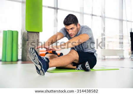 Portrait of a fitness man doing stretching exercises at gym  Royalty-Free Stock Photo #314438582