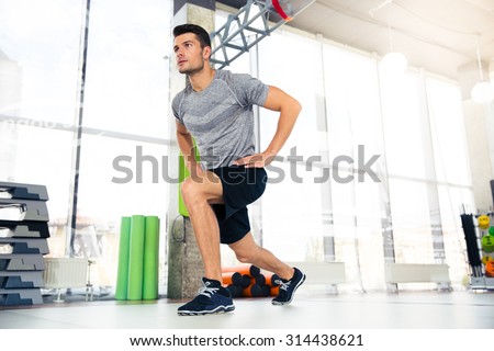 Portrait of a handsome fitness man doing warm-up exercises at gym