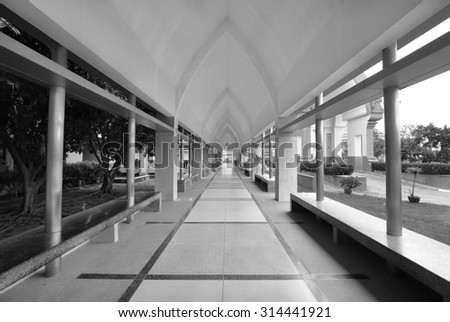 long empty corridor between garden and building (monochrome background)