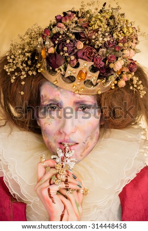 Studio art photo of the girl in the image of the Queen on a gold background. the art of makeup.

