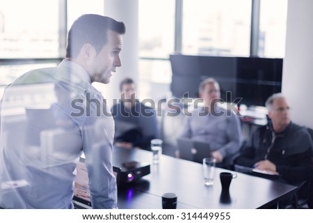 Business man making a presentation at office. Business executive delivering a presentation to his colleagues during meeting or in-house business training, explaining business plans to his employees. Royalty-Free Stock Photo #314449955