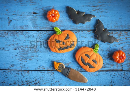 Homemade gingerbread cookies in the form as Halloween  jack-o-lantern pumpkins and bats, maple and oak leaves on the blue wooden table. Space for text  and selective focus.