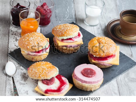 Sweet cake in the form of a burger, strawberry mousse with white chocolate and roll with sesame seeds on wooden table,, cooking background