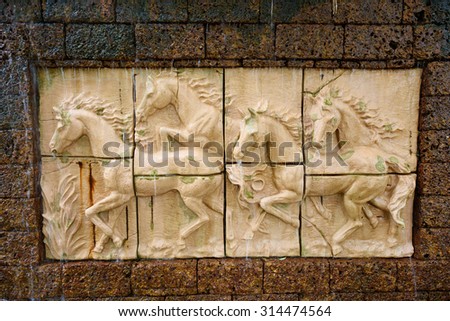 Stone sculpture of horse on brick wall with waterfall