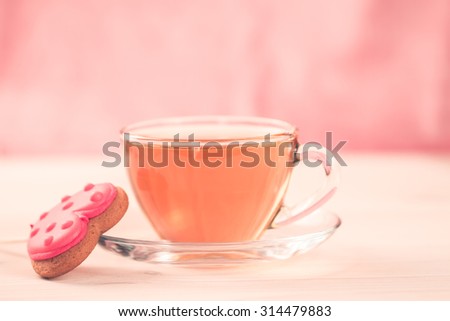delicious fresh cookies in the shape of a heart on a white plate on wooden background. A Cup of green tea.Breakfast