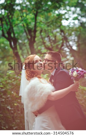 happy newlyweds kissing and embracing surrounded by pastel blurred background