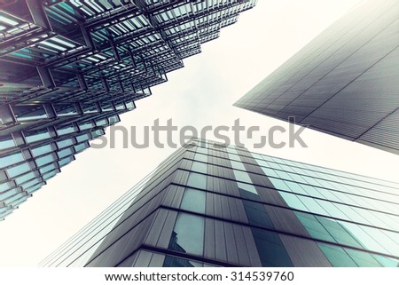 An abstract coloured vintage image, looking up capturing three different buildings on a 45 degree angle with an applied vintage filter to produce green and blue tint to the photo.