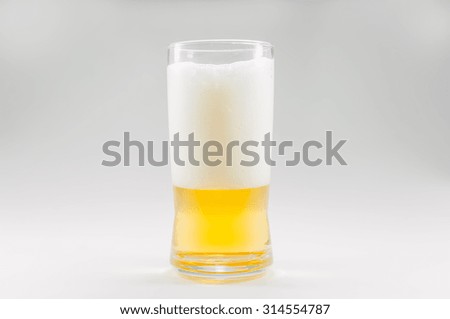 Glass of fresh beer with cap of foam isolated on white background
