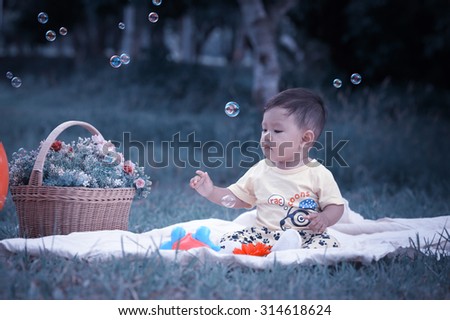 Asia Baby boy sitting on green grass in the park with soap bubbles