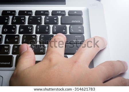 Close up hands with laptop and focus on enter button (English - Thai language)