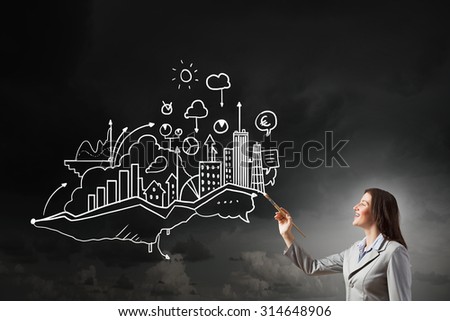Young attractive businesswoman with paint brush and business sketches on wall