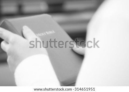 De focused or blurred image for a woman holding holy bible in the church for religion background in white and black color tone
