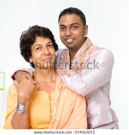 Portrait of beautiful Indian family at home. Mature 50s Indian mother and her 30s grown son.