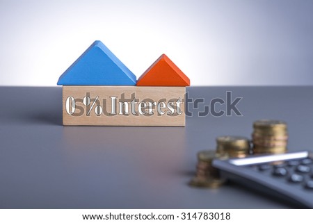 Housing Loan concept. House Wooden Block, coins and calculator with word 0% Interest
