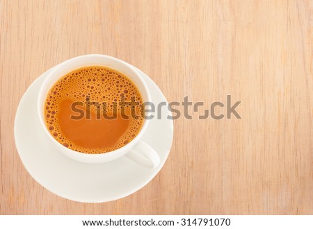 Hot milk tea in a white cup on wooden background Royalty-Free Stock Photo #314791070