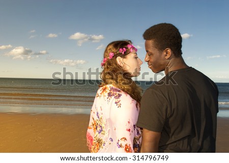 Young couple multicultural head and shoulders  looking into each others eyes in love on beach  romantic emotions