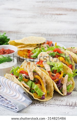 Mexican tacos with chicken, bell peppers, black beans and fresh vegetables