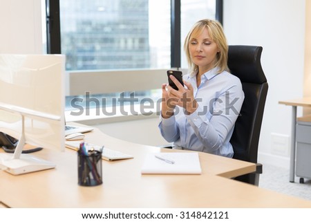 Middle aged business woman working at office. Using smartphone