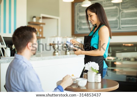Beautiful young waitress swiping a credit card from a customer in a bank terminal