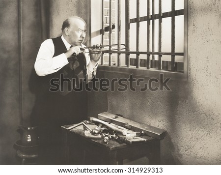 Man sawing through bars Royalty-Free Stock Photo #314929313