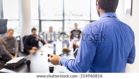 Business man making a presentation at office. Business executive delivering a presentation to his colleagues during meeting or in-house business training, explaining business plans to his employees.  Royalty-Free Stock Photo #314960816