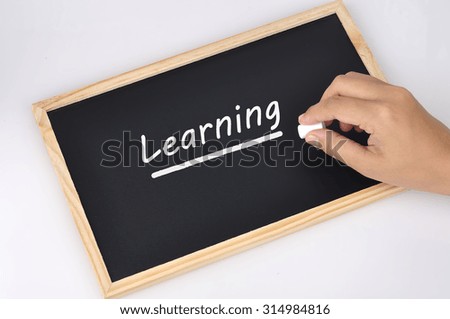 Women Hand Holding Chalk Writing "Learning" Word On Black Board