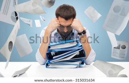 business, people, deadline, stress and paperwork concept - sad businessman with stack of folders and falling papers over blue background Royalty-Free Stock Photo #315031634