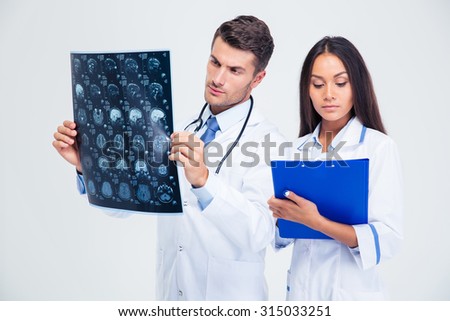 Portrait of a male doctor looking at x-ray picture of brain and woman writing diagnose isolated on a white background