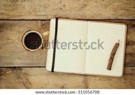 top image of open notebook with blank pages, next to pine cones and cup of coffee over wooden table. top image, 
