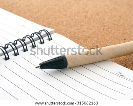 Opened blank notebook with pen on wooden background.