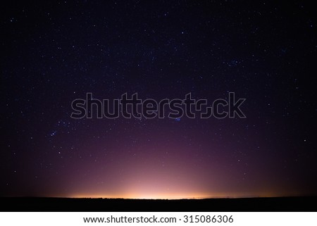 Colorful Night Starry Sky Above The Yellow City Lights. Night Glowing Stars