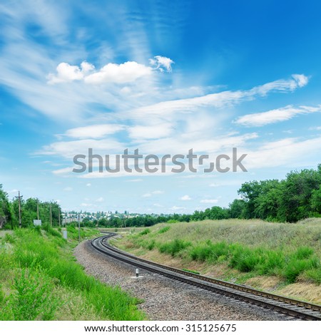 railroad to green horizon and clouds in blue sky over it