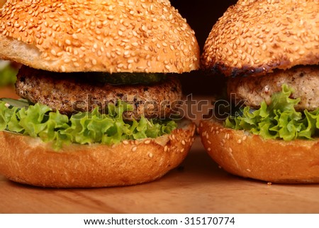 Few big delicious appetizing fresh burgers of green lettuce leaf cheese meat cutlet and white bread bun with sesame seeds closeup, horizontal picture