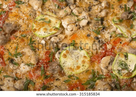 Surface of italian fresh baked hot aromatic pizza with chicken ham bacon mushrooms tomato red paprika zucchini covered with shaved cheese and mozzarella and green onion closeup, horizontal picture