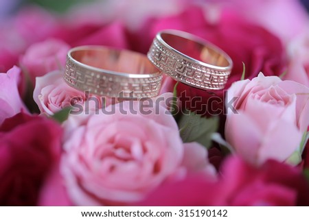 Closeup of one beautiful pink and red fresh rose flower bouquet with two wedding golden rings, horizontal picture