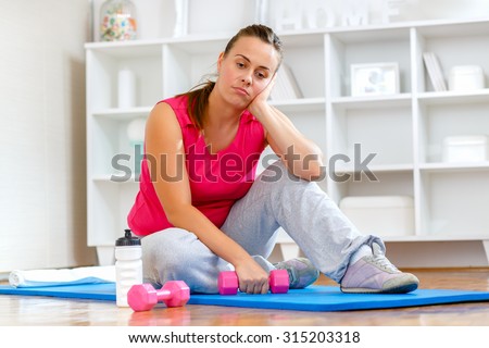Tired young woman struggling to get back into shape.  Royalty-Free Stock Photo #315203318