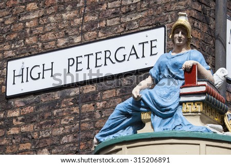 The street sign for High Petergate in York with a statue of Minerva - the Goddess of Wisdom and Learning.  The statue is a reminder of when the street was the home of many booksellers and bookbinders.