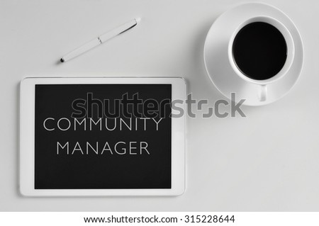 high-angle shot of a white table with a pen, a cup of coffee and a tablet computer with the text community manager written in its screen