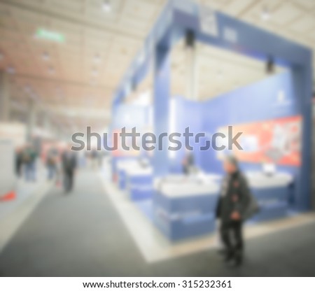 People visit a fair, generic event background, intentionally blurred post production.