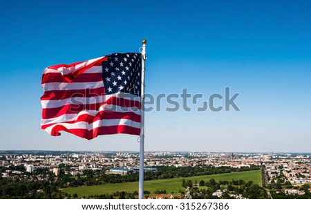 american flag waving in the sky on a town background