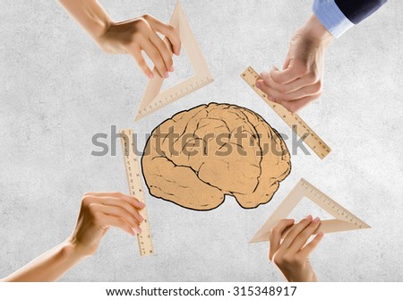 Close up of people hands measuring brain with ruler