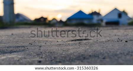 Little city or village in a sunset time. View from the level of asphalt with selective focus
