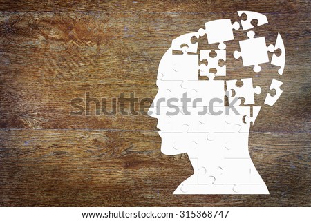 Human head as a set of puzzles on the wooden background Royalty-Free Stock Photo #315368747