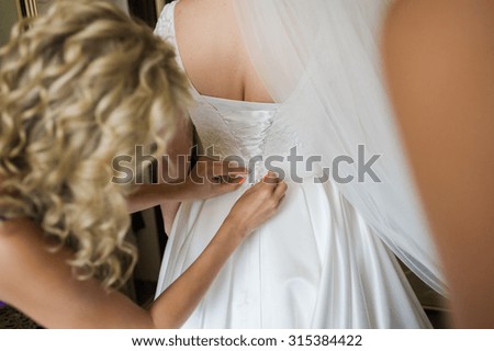 bridesmaids help the bride on the morning of the wedding day to prepare for the ceremony