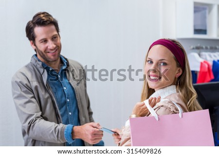 Portrait of smiling woman getting back credit card in clothing store