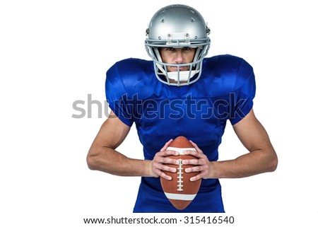Portrait of confident American football player holding ball against white background