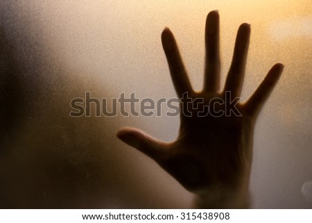 Shadow of hand behind wet glass, close-up