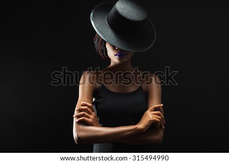 dark skinned woman on a black background with a fashionable hat on his head