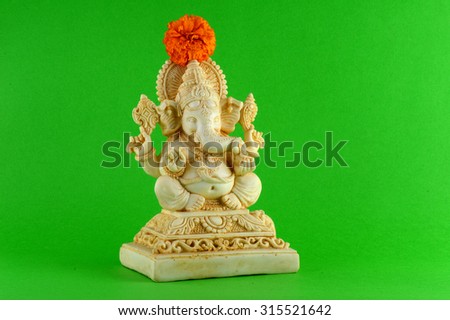 Hindu God Ganesha. Ganesha Idol on Green Background with flowers. 