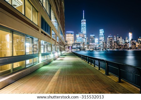 Waterfront walkway and view of the Lower Manhattan skyline at night, at Exchange Place in Jersey City, New Jersey.